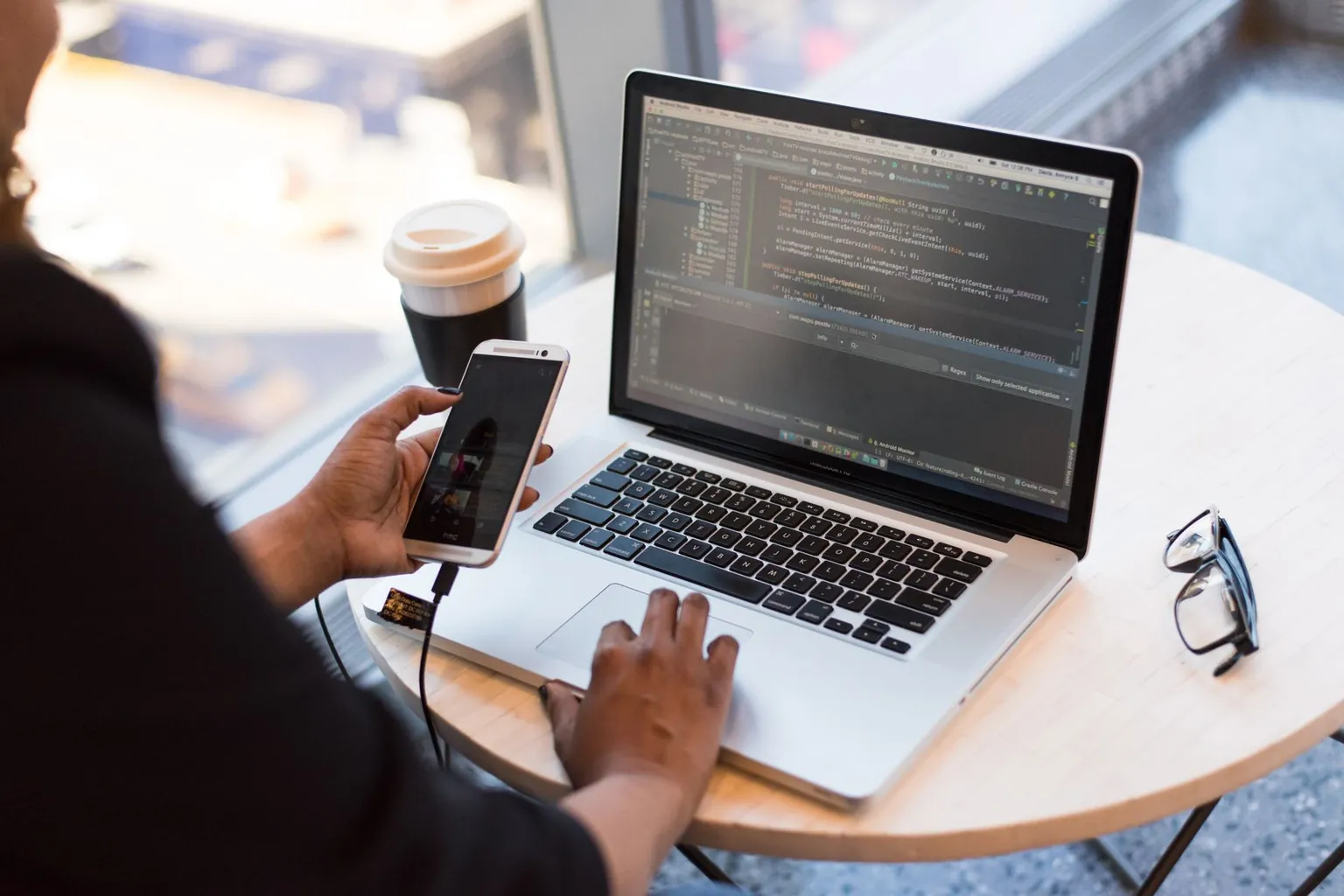 Marketer managing automated customer conversations on a phone and laptop